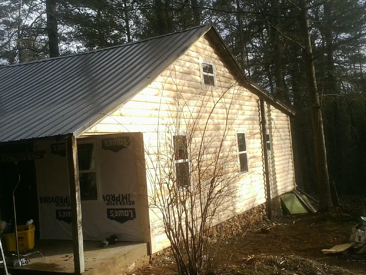 Log siding gable end under a dark metal roof edge in Olustee