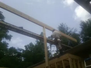 Carpenter setting a ridge beam over a new addition frame — Ice Dam Removal by Roofing Brothers in Olustee