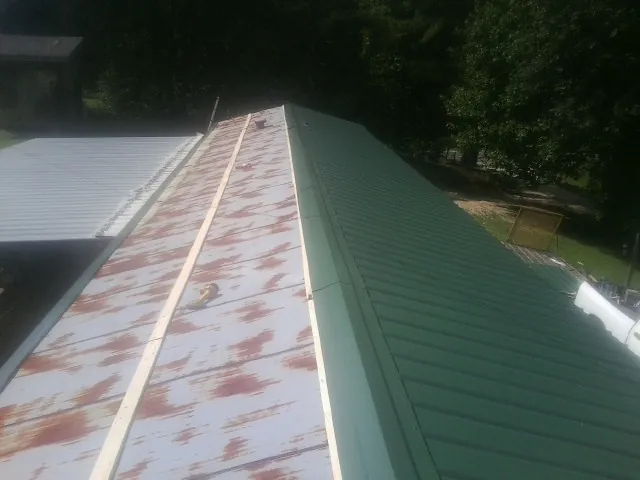 Old rusted panels beside newly installed green metal roofing — Wind Damage Roof Repair by Roofing Brothers in Olustee
