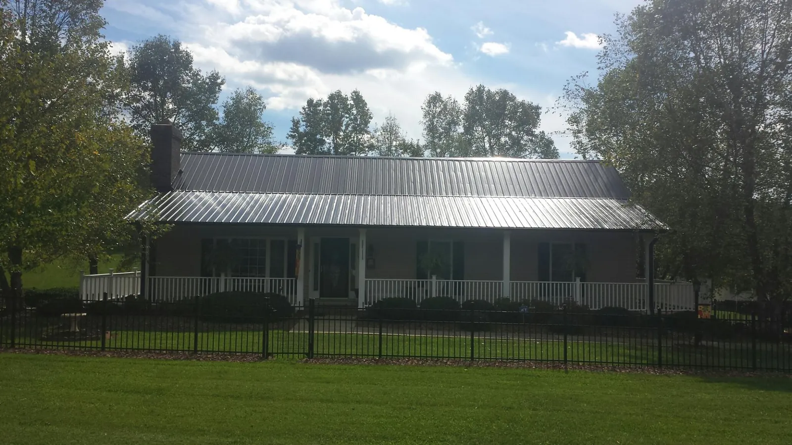 Gray metal roof on a brick ranch with a full width front porch — Gutter Guard Installation work by our crew in Olustee
